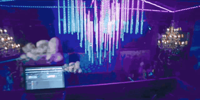 a laptop is on a table in front of a purple chandelier