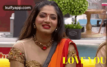 a woman in a saree is smiling and looking at the camera .