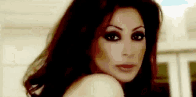 a close up of a woman 's face with long dark hair and a very serious look on her face .