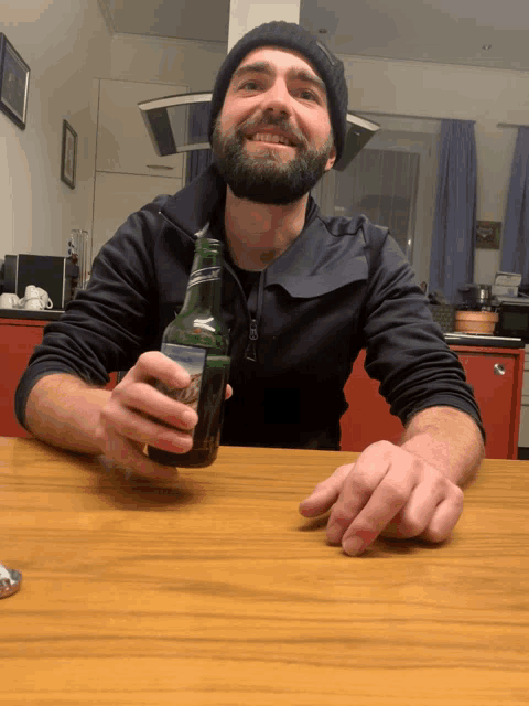 a man is sitting at a table holding a bottle of beer with a label that says " pilsner "