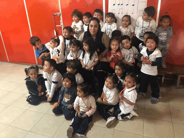 a group of children are posing for a picture with a woman wearing a shirt that says ' a ' on it