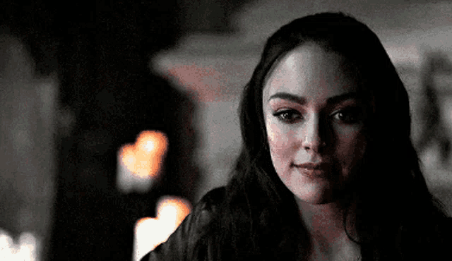 a woman is looking at the camera in a dark room .