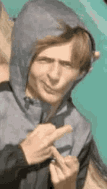 a man in a hoodie is making a funny face and giving the middle finger .