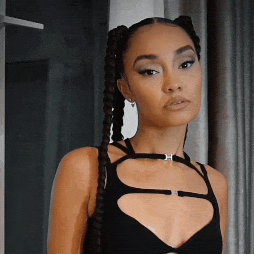 a woman wearing a black braided top has a choker with the letter h on it