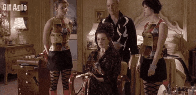 a gif of a woman sitting in a chair with a man standing behind her with the words gif agio below her