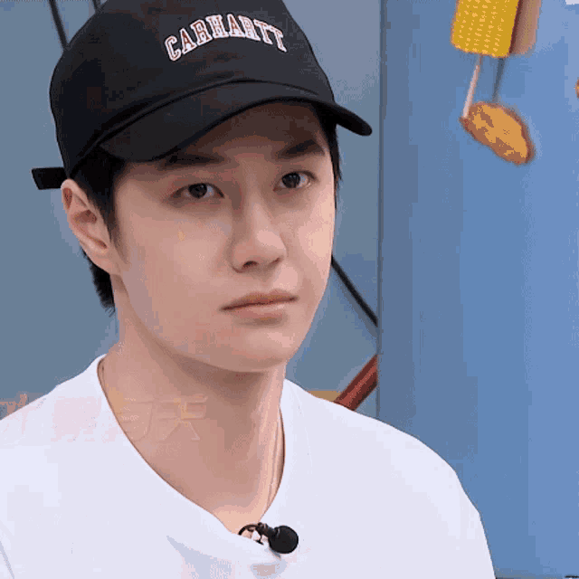a young man wearing a black carhartt hat and a white shirt