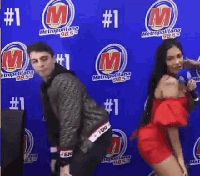 a man and a woman are dancing in front of a wall that says metropolitana on it