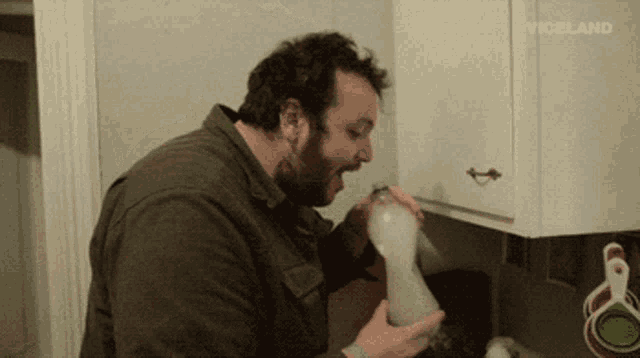 a man is drinking from a bottle in a kitchen with a viceland logo in the background
