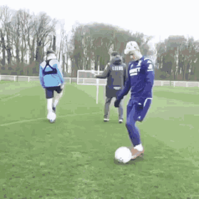 a man is kicking a soccer ball on a field while a man watches .