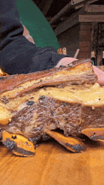 a person is holding a large piece of meat on a wooden surface