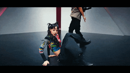 a woman in a colorful crop top is kneeling down on the floor