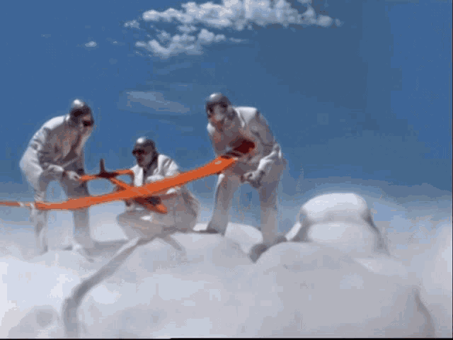 a group of men standing on top of a cloud holding a red plane