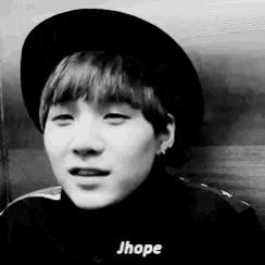 a black and white photo of a young man wearing a hat and a turtleneck sweater .