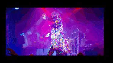 a man in a colorful outfit is singing into a microphone on stage