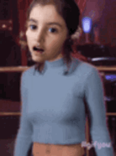 a young girl in a blue crop top is standing in a room .
