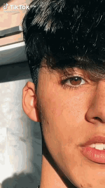 a close up of a young man 's face with a piercing in his ear and red lips .