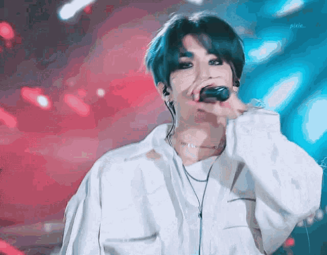 a man with blue hair is singing into a microphone while wearing headphones .