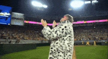 a man in a dalmatian coat is clapping in front of a budweiser sign
