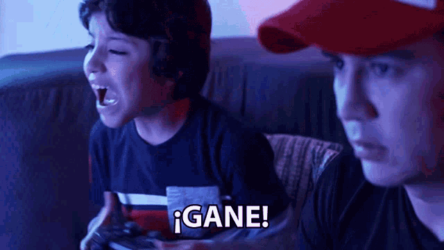 two boys are playing a video game and one of them is saying gane