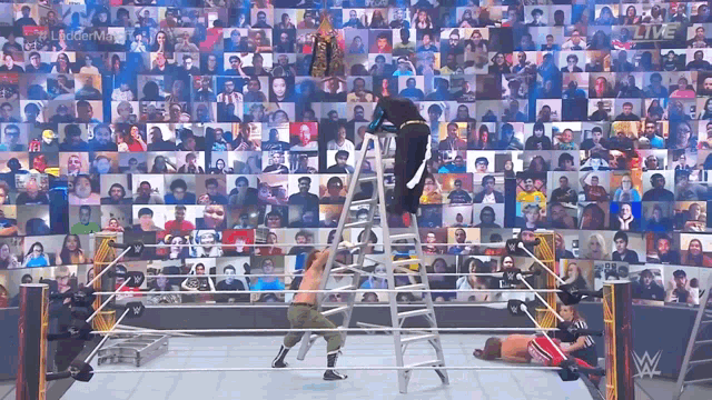 a wrestling match is being shown live on a large screen