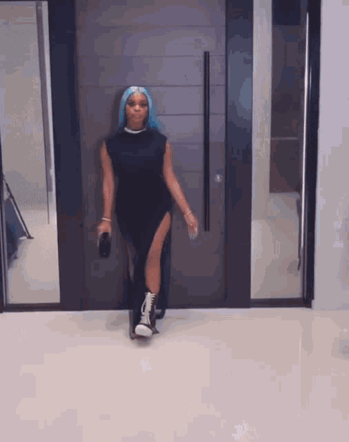 a woman with blue hair is standing in front of a door .
