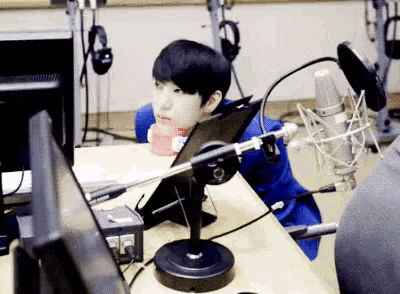 a man is sitting at a desk with a microphone and a monitor