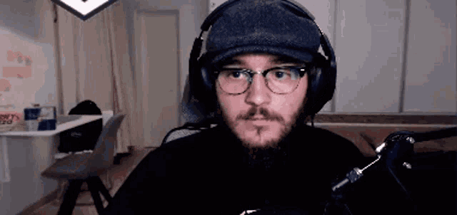 a man with a beard wearing headphones and glasses looks at the camera .
