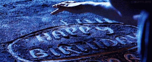 a person is writing the word happy birthday on the ground .