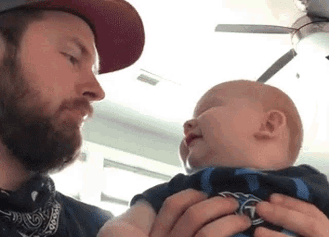 a man is holding a baby in his arms and looking at it .