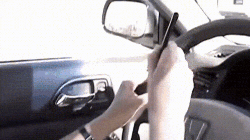 a person is holding a cell phone in their hand while driving