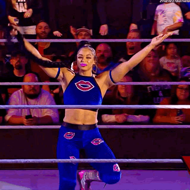 a woman in a blue top with lips on it is kneeling in front of a crowd