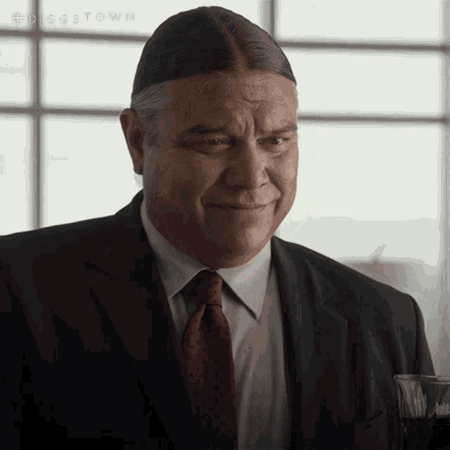 a man in a suit and tie is smiling in front of a window with the word dogetown on the bottom