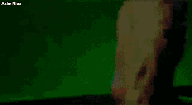 a group of people are dancing in a room with green lights and the words asim riaz on the bottom
