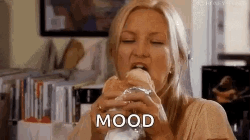 a woman is eating a sandwich wrapped in tin foil and the word mood is written on the screen .