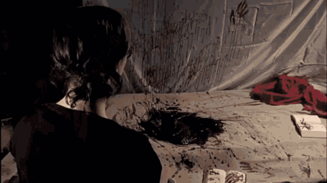 a person is sitting on a bed with blood on the floor