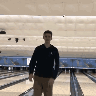 a man in a black jordan shirt is standing on a bowling alley