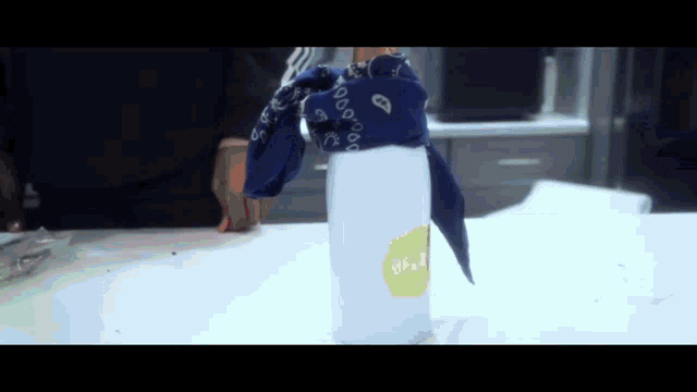 a blue bandana is wrapped around a white bottle with a yellow sticker that says ' lemon ' on it