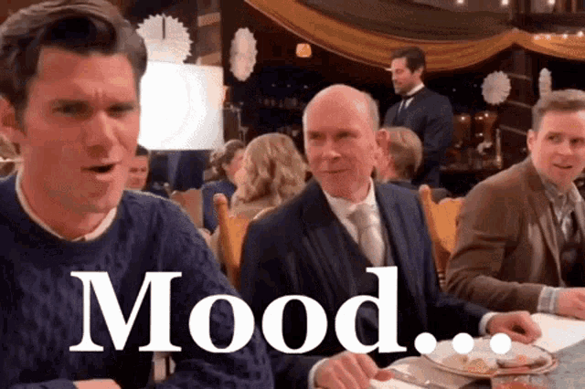 a group of men are sitting at a table and the word mood is on the screen