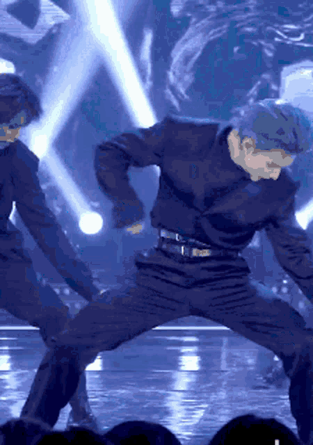 a man in a black suit is dancing on a stage in front of a crowd