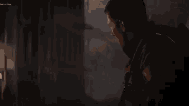 a man is standing in a dark room with smoke coming out of the ceiling .