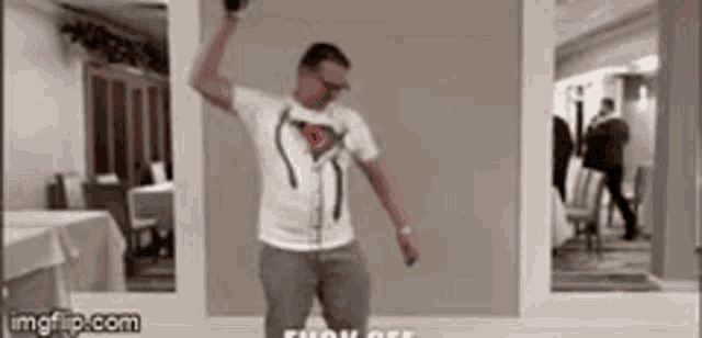 a man in a white shirt is dancing in front of a mirror .