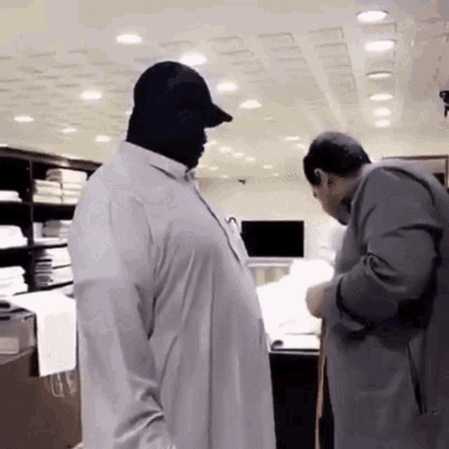 a man in a white shirt is standing next to another man in a gray jacket