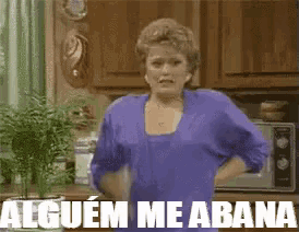 a woman in a blue shirt is standing in a kitchen with the words alguem me abana on the bottom