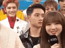 a woman is holding a microphone in front of a group of people and talking to a man .