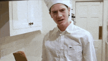 a man wearing a chef hat and a white shirt with a lacoste logo on the pocket