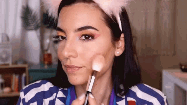 a woman wearing a headband with cat ears is applying makeup