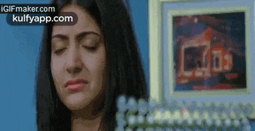 a woman is crying in front of a framed picture of a house .