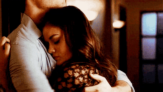 a man and a woman are hugging each other in a room in front of a window .