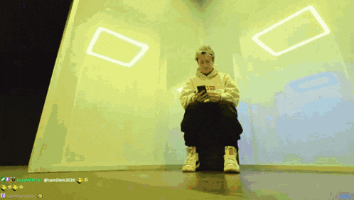 a person sitting in front of a wall with a yellow square on it that says ' camillem2020 ' on it