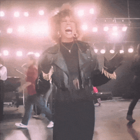 a woman in a leather jacket is singing on stage